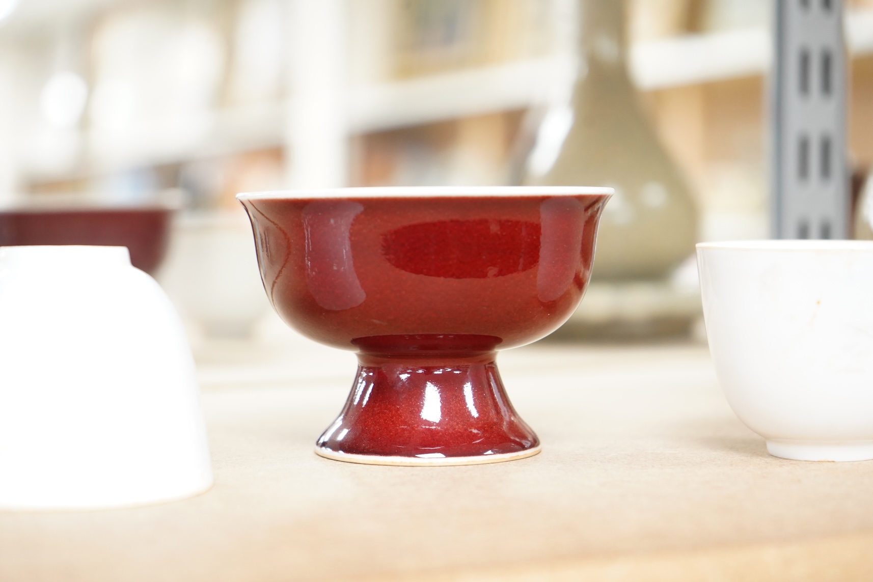 A Chinese red glazed stem cup together with two white glazed tea bowls, tallest 6.5cm